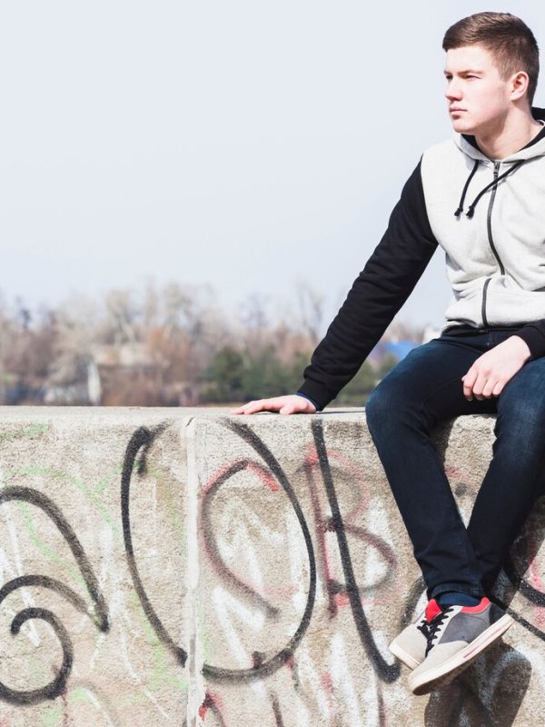 young-man-sitting-graffiti-wall_23-2147839381